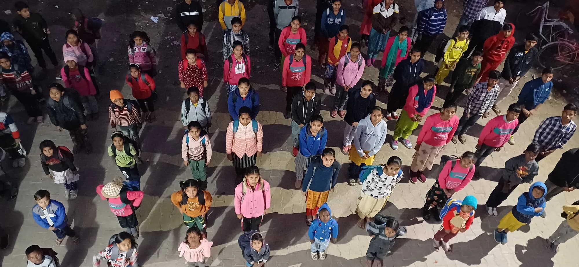 Children of the centre standing in rows in the yard at assembly, seen from above